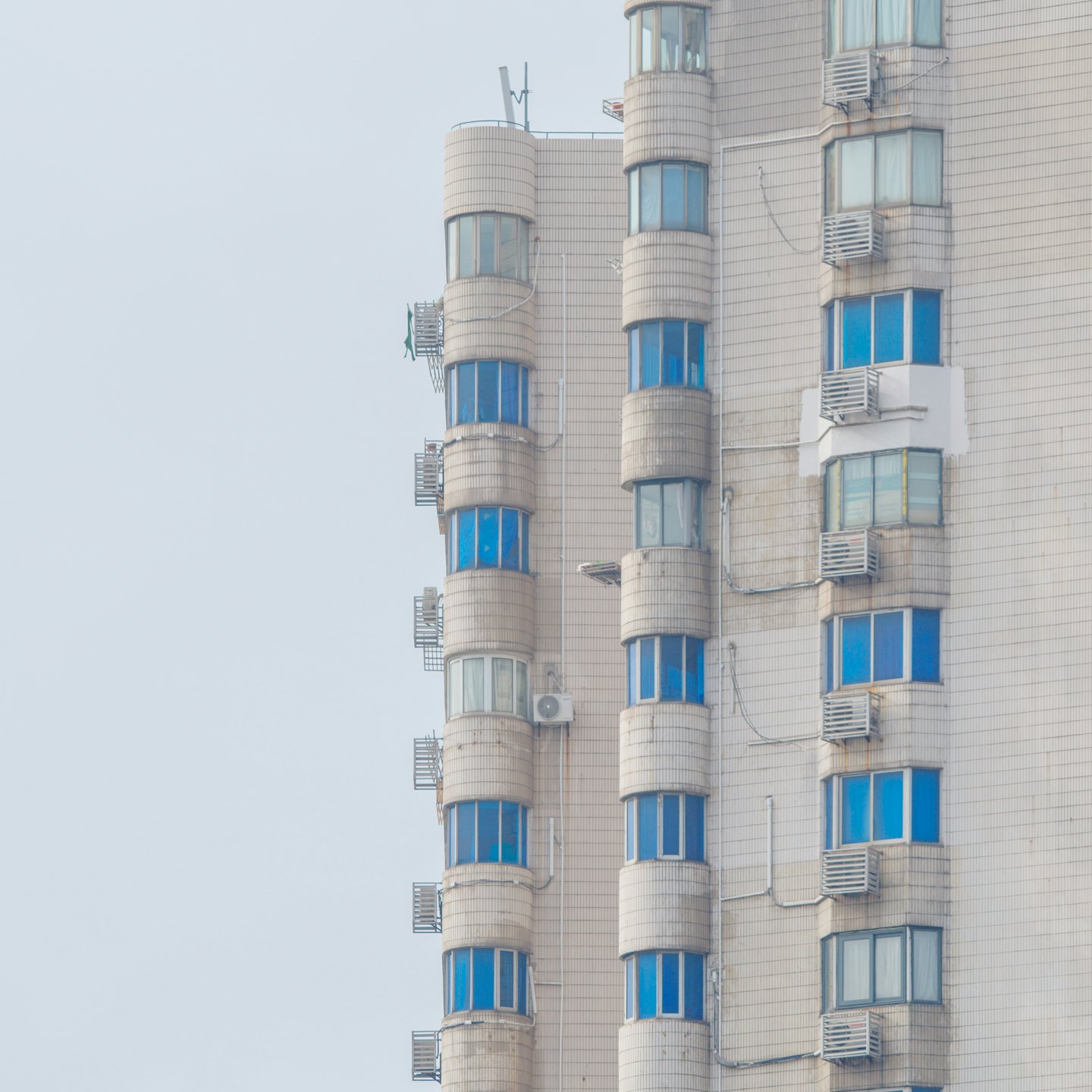 Tiled residential building facade with curved balconies and blue windows.